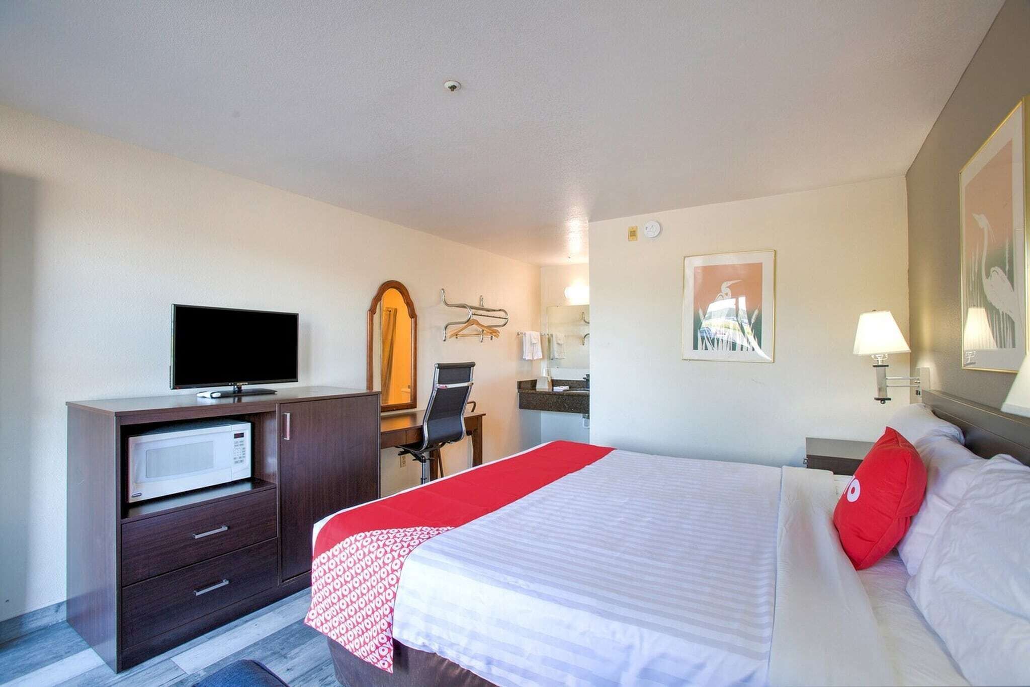 A hotel room with a bed, a TV, a microwave, a desk, and a chair.