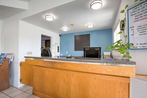 Un mostrador de recepción con encimera de madera, pared azul y un cartel con instrucciones.
