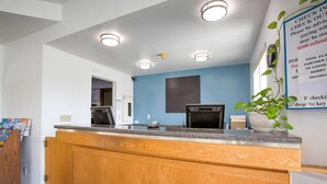 A reception desk with a wooden counter, a blue wall, and a sign with instructions.