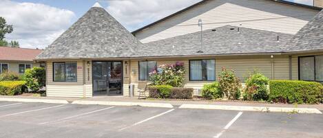 A single-story building with a gabled roof, a small attached office, and a parking lot.