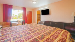 A hotel room with a bed, a desk, a chair, a television, and a wardrobe. - Weslaco TX|King Bed Smoking (Weslaco TX)