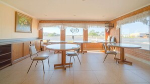 A restaurant with round tables and chairs, a ceiling fan, and a view of the outside. - Weslaco TX|King Bed Smoking (Weslaco TX)