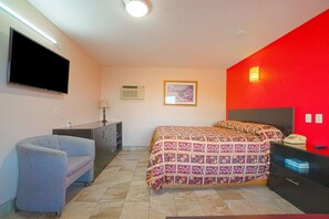 Een slaapkamer met een bed, een televisie, een bureau en een stoel.