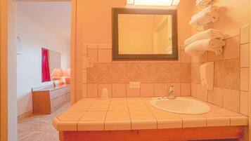 A bathroom with a sink, mirror, towel rack, and a toilet.