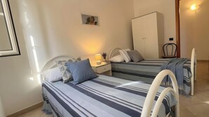 A bedroom with two beds, a nightstand, a wardrobe, and a chair.