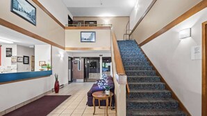 A hotel lobby with a reception desk, a staircase, and a sofa.