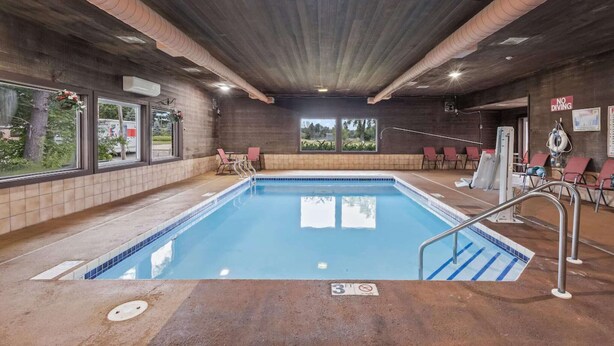 An indoor swimming pool with clear glass walls, a tiled floor, and a ceiling with visible ductwork.