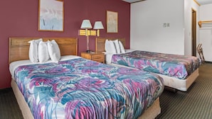 A hotel room with two beds, a wooden headboard, a nightstand, a lamp, and wall art.