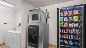 A utility room with a water dispenser, a washing machine, and a vending machine with snacks.
