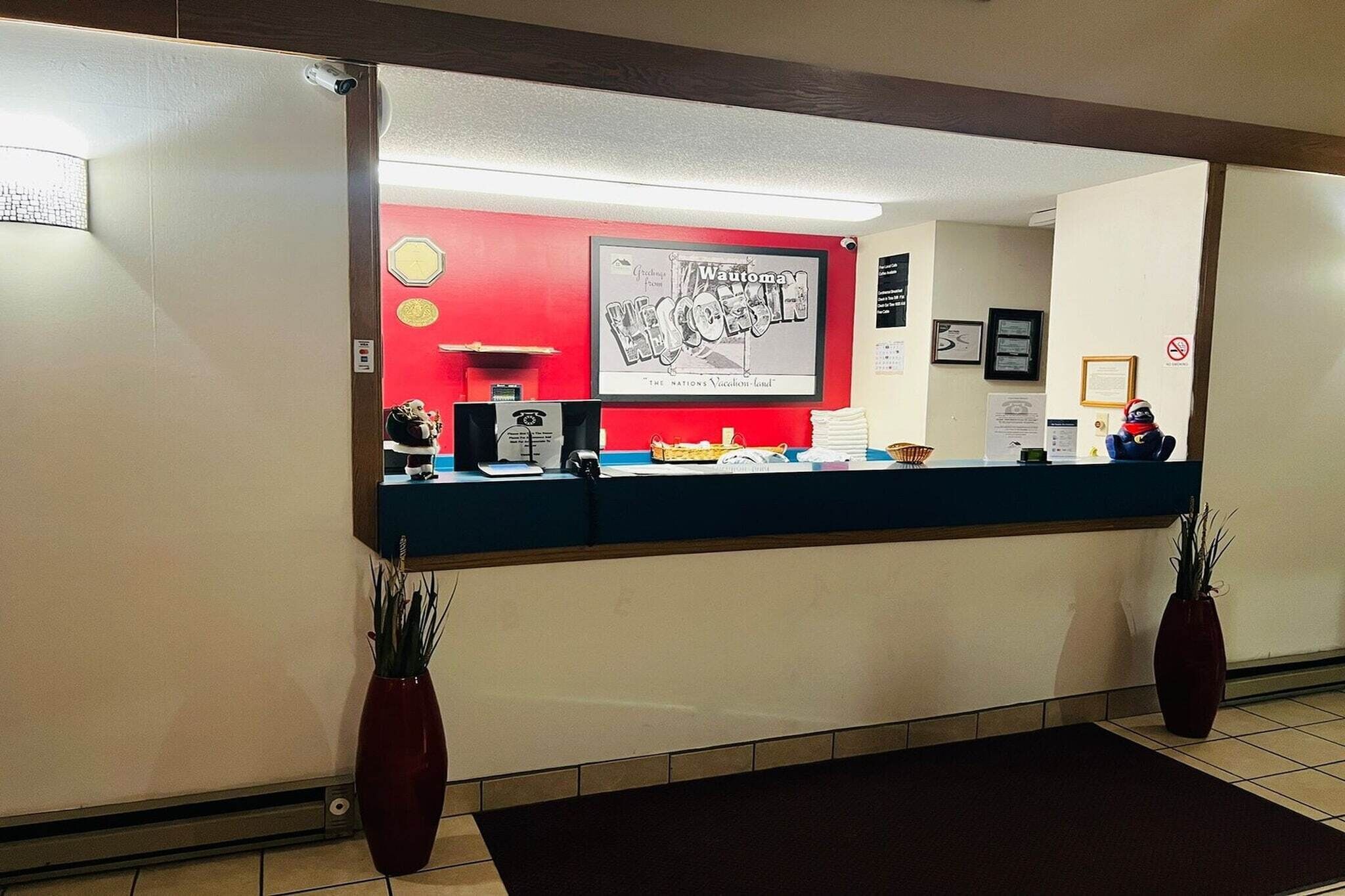 A reception desk with a red wall, framed artwork, and a no-smoking sign.