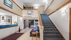 A hotel lobby with a reception desk, a staircase, and a sofa.