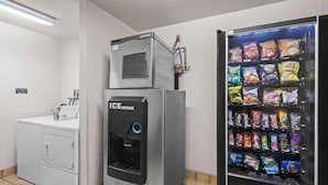 A utility room with a water dispenser, a washing machine, and a vending machine with snacks.