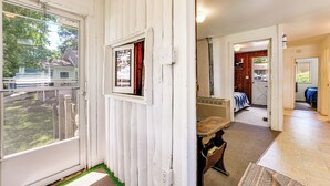 Une pièce dotée d’une grande fenêtre, d’une porte en bois, d’une petite table et offrant une vue sur l’extérieur.