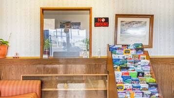 A reception area with a wooden desk, a 'No Smoking' sign, a framed picture, and a display of travel guides.