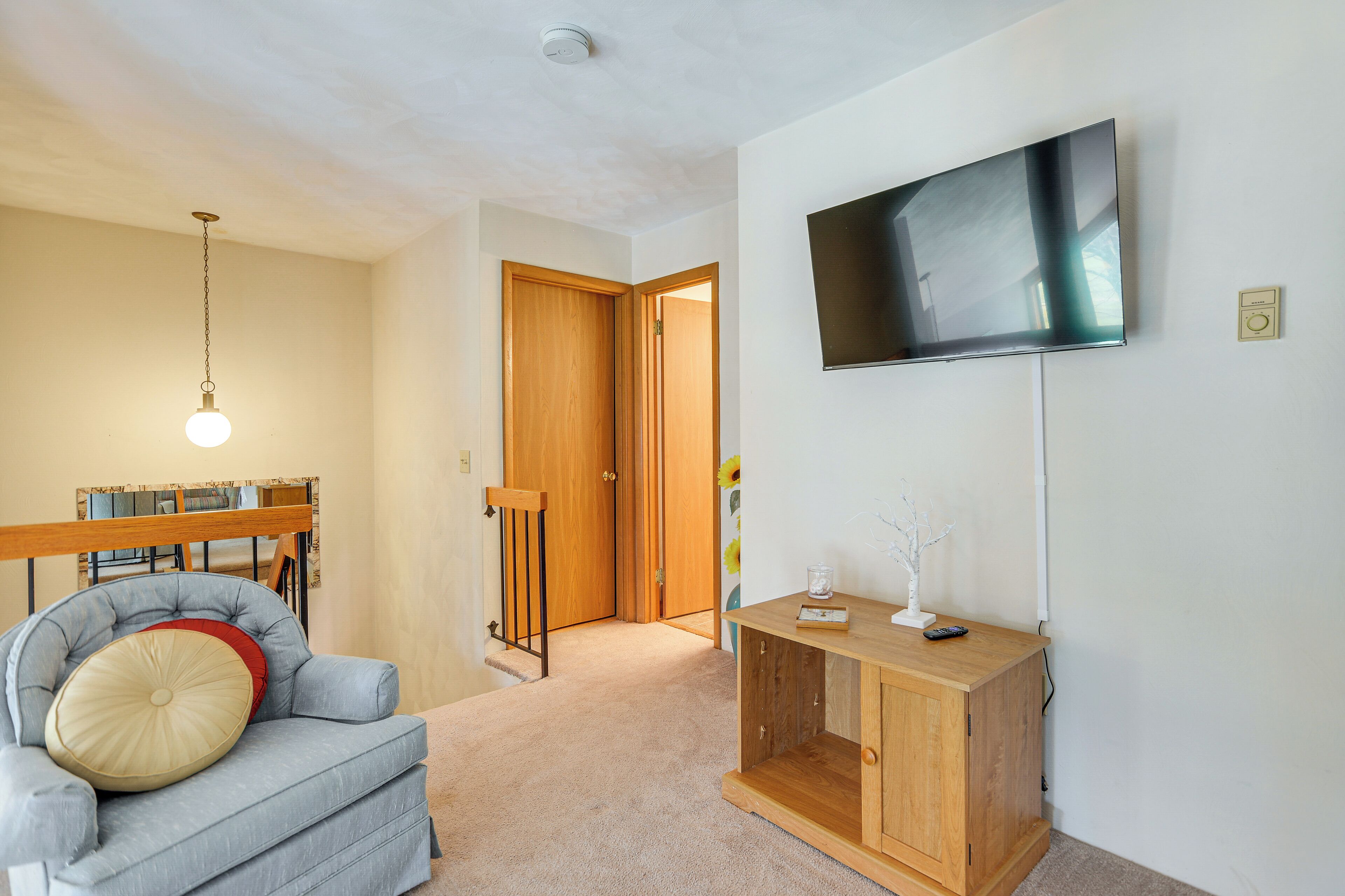 A living room with a sofa, a wooden cabinet, a television, and a ceiling light.