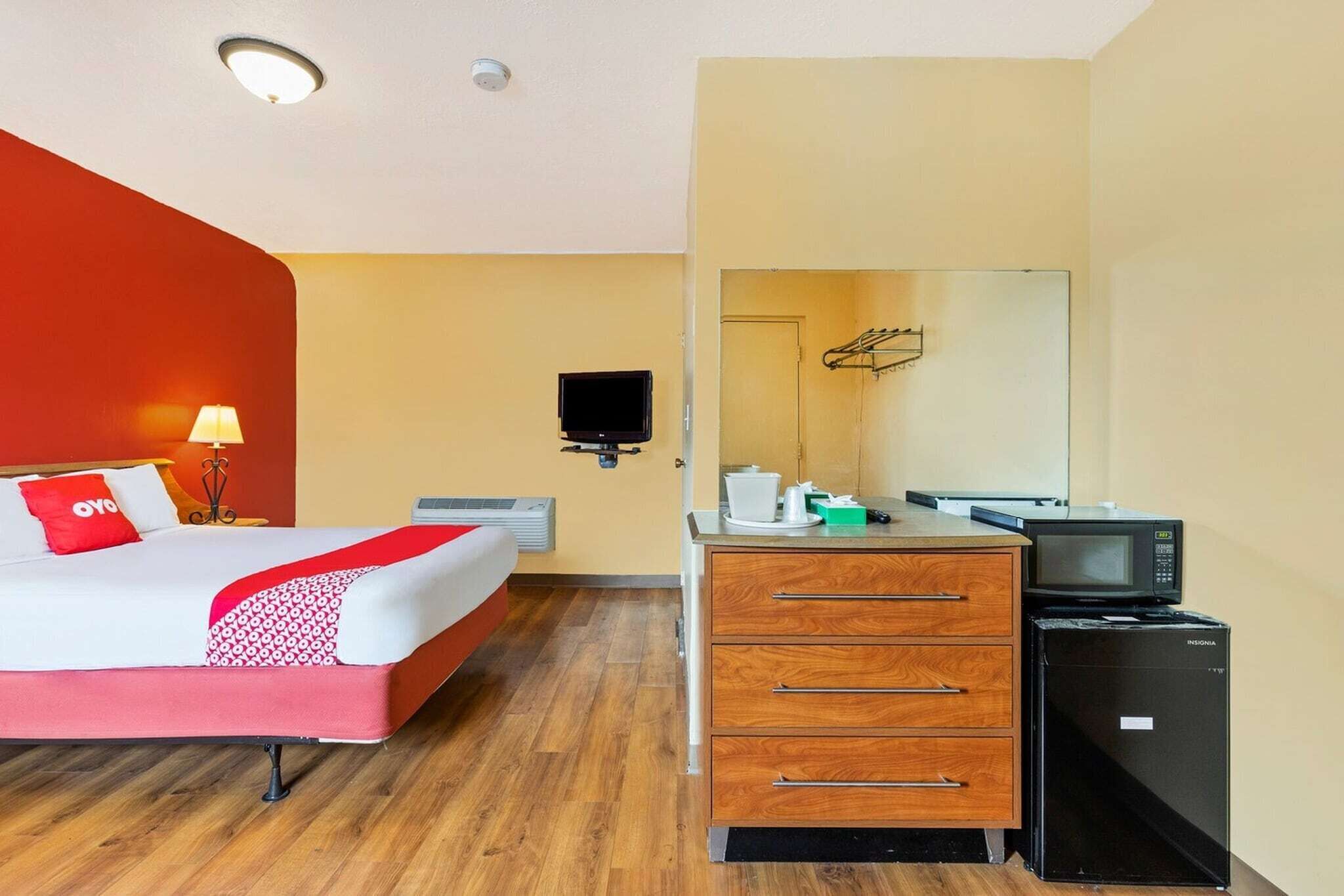 Ein Hotelzimmer mit einem Bett, einem Nachttisch aus Holz, einer Mikrowelle und einem Fernseher.