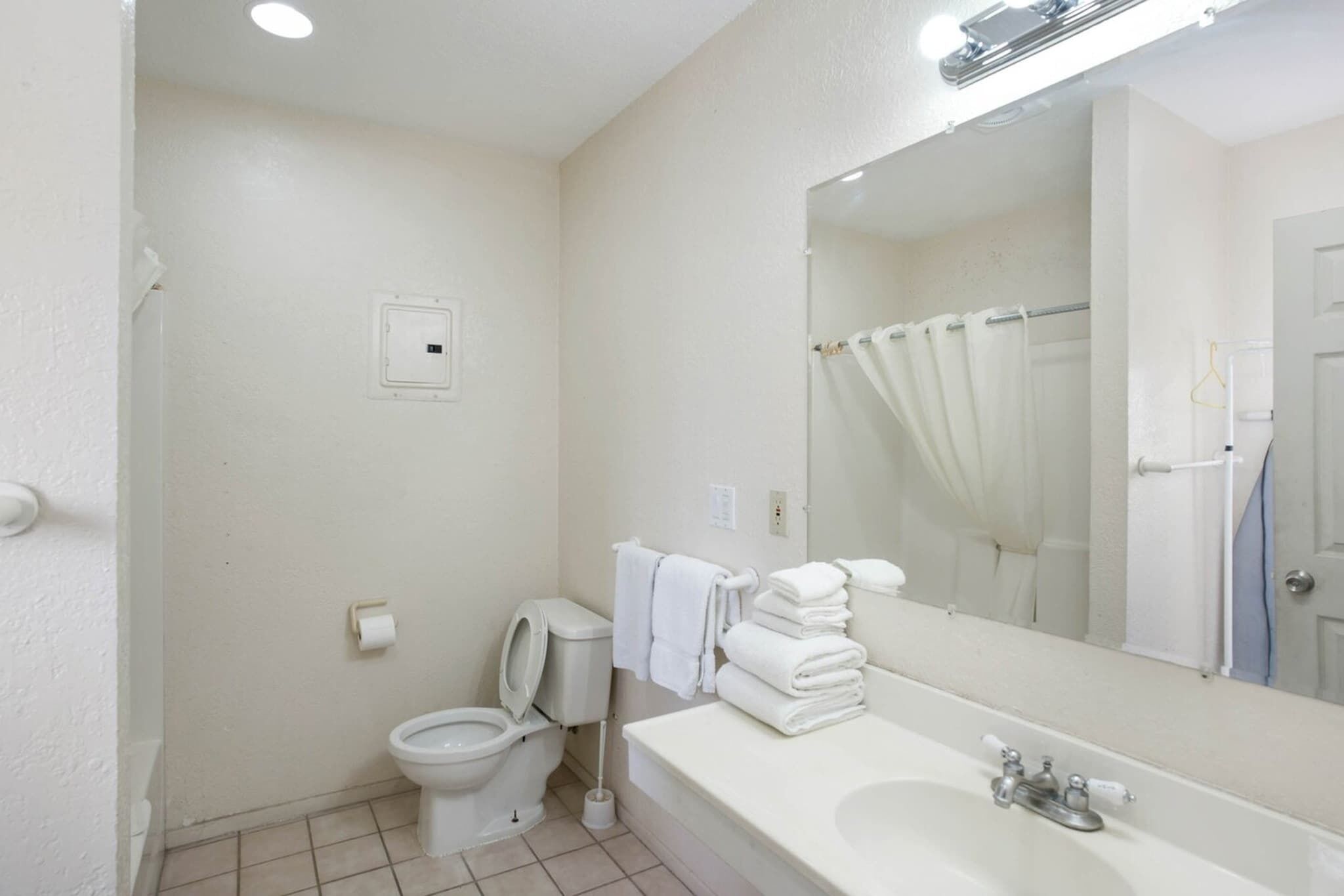 Baño con inodoro, lavamanos, espejo y cortina de ducha.