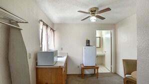 Eine kompakte Küche mit Deckenventilator, Kühlschrank, Mikrowelle und einem kleinen Tisch.