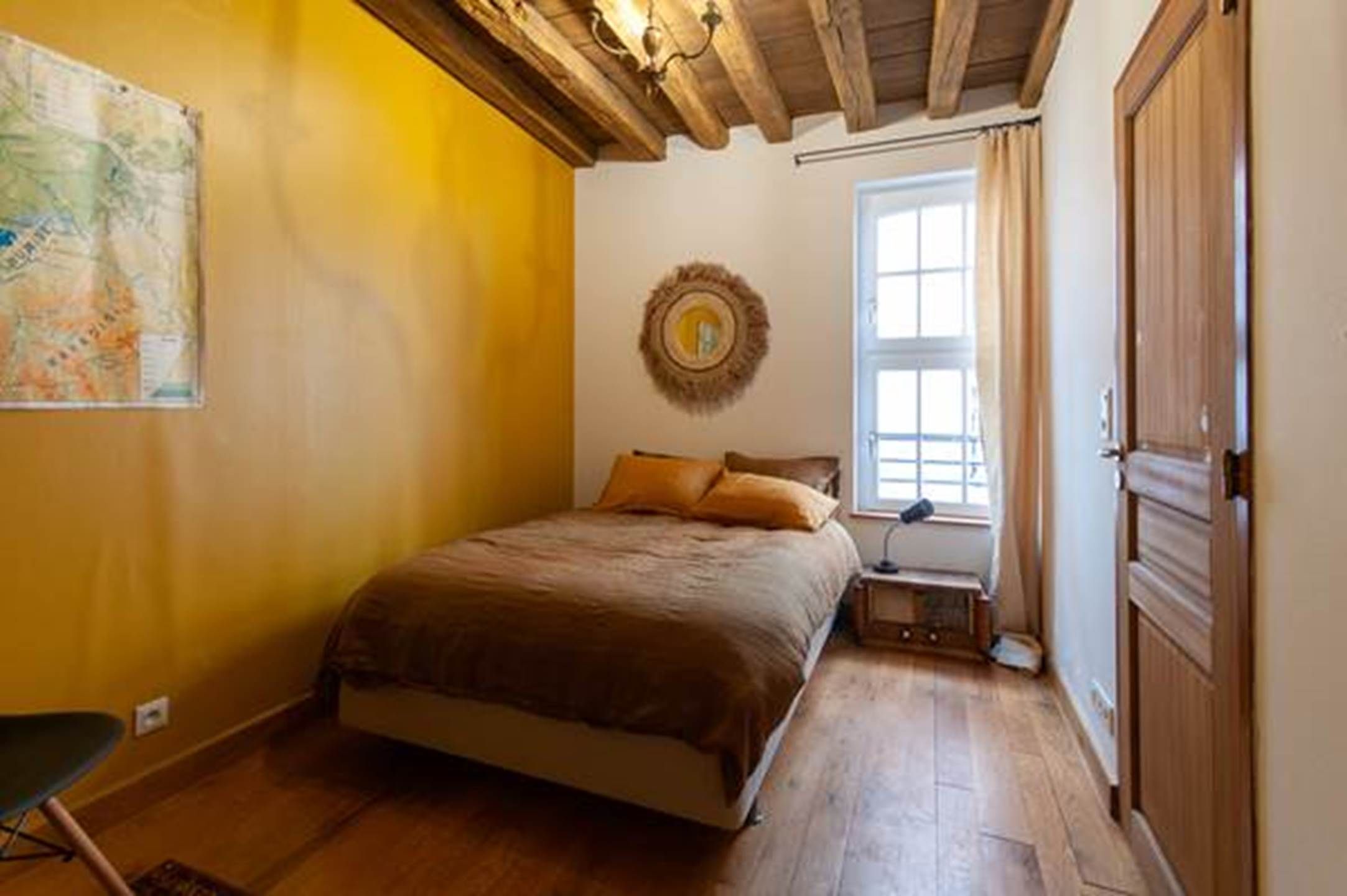 Une chambre à coucher avec un lit, une fenêtre, une porte et un élément de décoration circulaire fixé au mur.