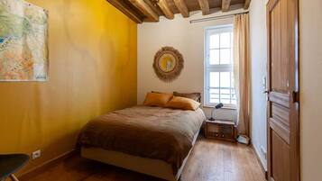 Une chambre à coucher avec un lit, une fenêtre, une porte et un élément de décoration circulaire fixé au mur.