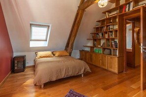 A bedroom with a sloped ceiling, a bed, a wooden bookshelf, and a window. - La Ruelle des Chats House, Historic Center of Troyes (Troyes)