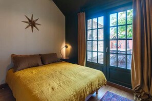 Ein Schlafzimmer mit einem Bett, einer Stern-Dekoration an der Wand, einem Nachttisch mit Lampe und Blick ins Freie durch ein Fenster.