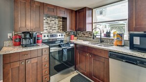 A kitchen with dark wood cabinets, a stainless steel range, a dishwasher, and a window with blinds. - Private Pool! Port Richey Home Near Coast & Trails (Port Richey)