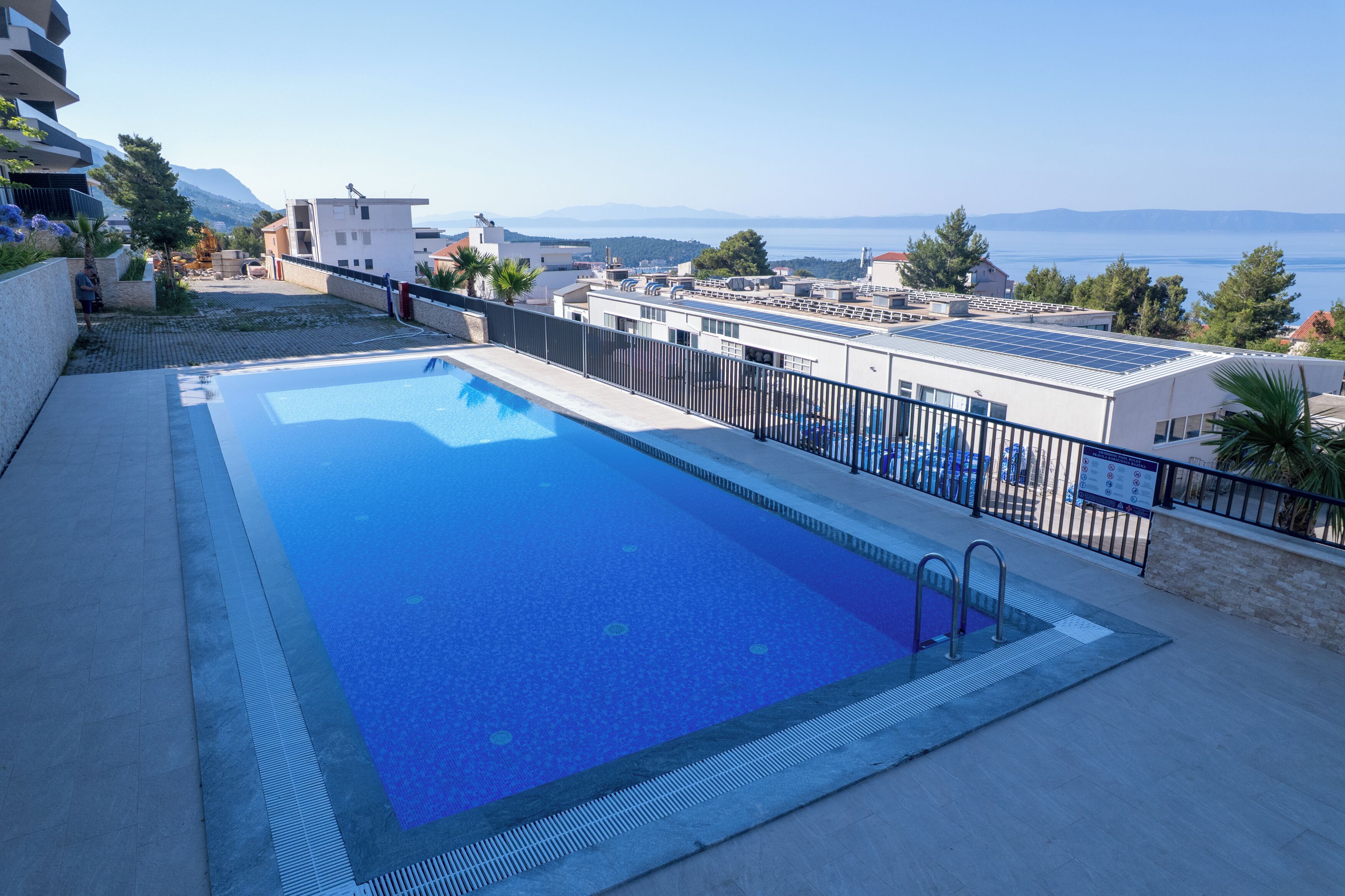 A rooftop pool with a clear view of the sea and mountains in the background.