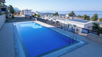 A rooftop pool with a clear view of the sea and mountains in the background.