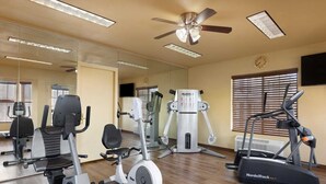 Un gimnasio con equipo de ejercicio, un ventilador de techo y un espejo grande.