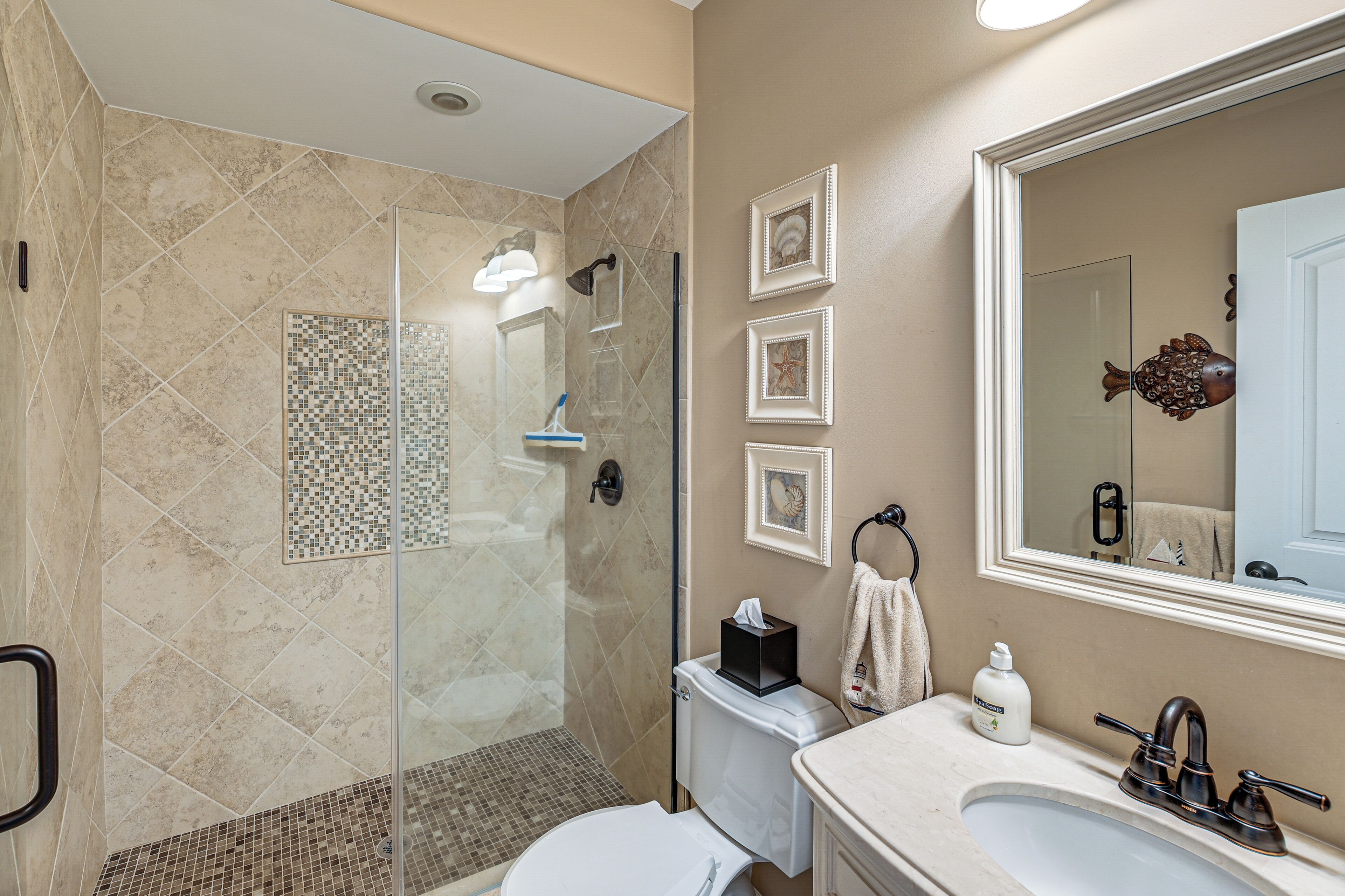 Une salle de bain avec une douche à parois de verre, des toilettes, un lavabo et un miroir.
