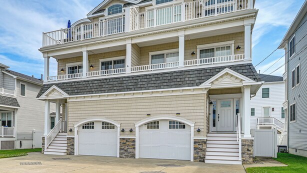 Une maison à deux étages avec un porche à l’avant, un garage et un balcon.