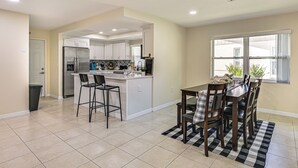 Una cocina moderna con una isla central, taburetes de bar y una mesa de comedor con sillas.