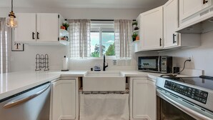 Uma cozinha moderna com armários brancos, geladeira de aço inoxidável, micro-ondas e fogão.