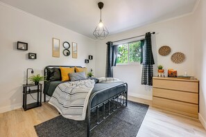 Ein modernes Schlafzimmer mit einem Bett, Nachttischen, einer Kommode und einem Fenster mit Vorhängen.
