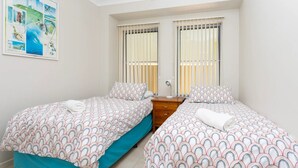 Une chambre double avec deux lits, une table de chevet et un tableau au mur.