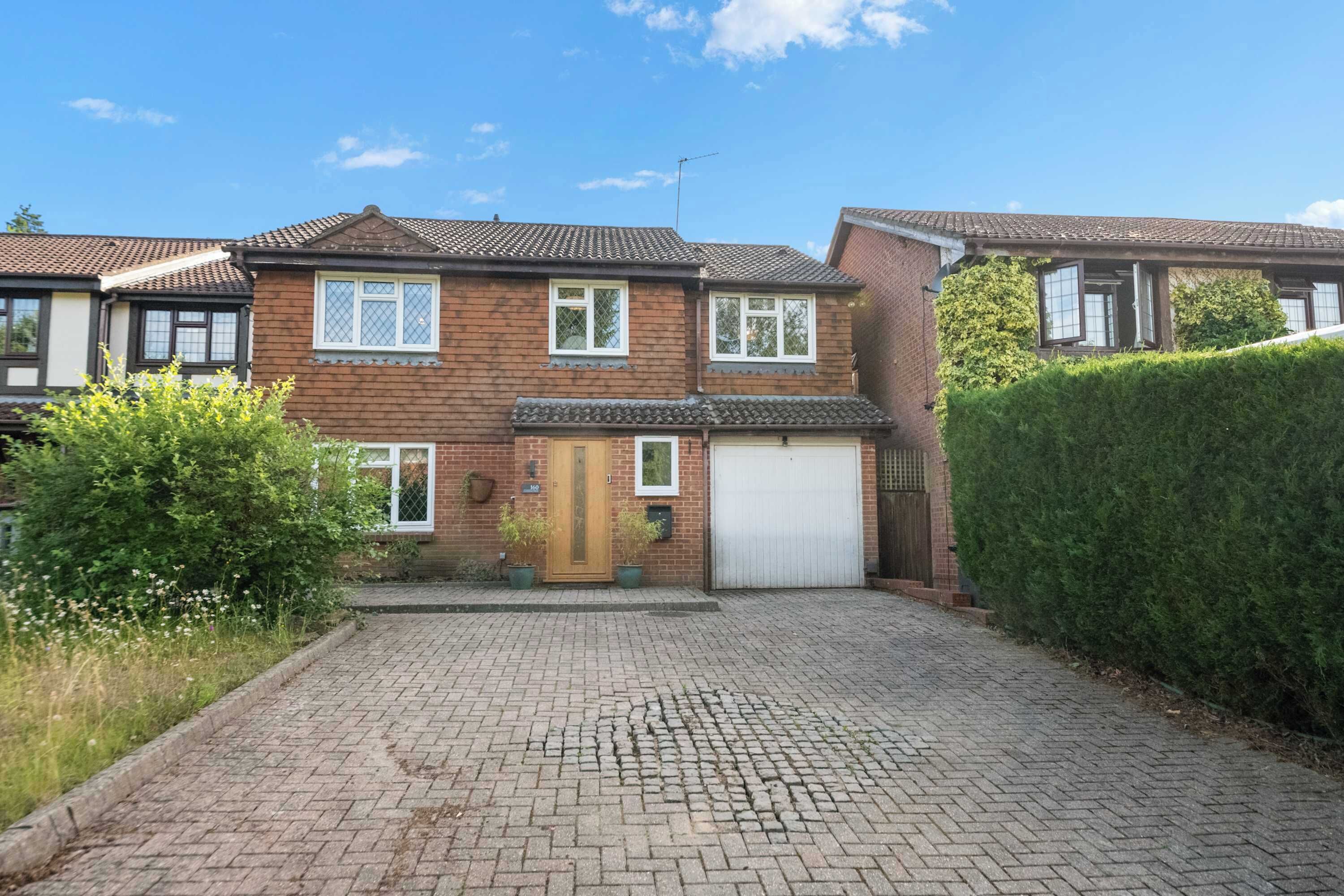 A two-story house with a paved driveway, a garage, and a well-maintained garden.