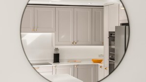 Una cocina moderna con armarios blancos, encimera negra y refrigerador de acero inoxidable.