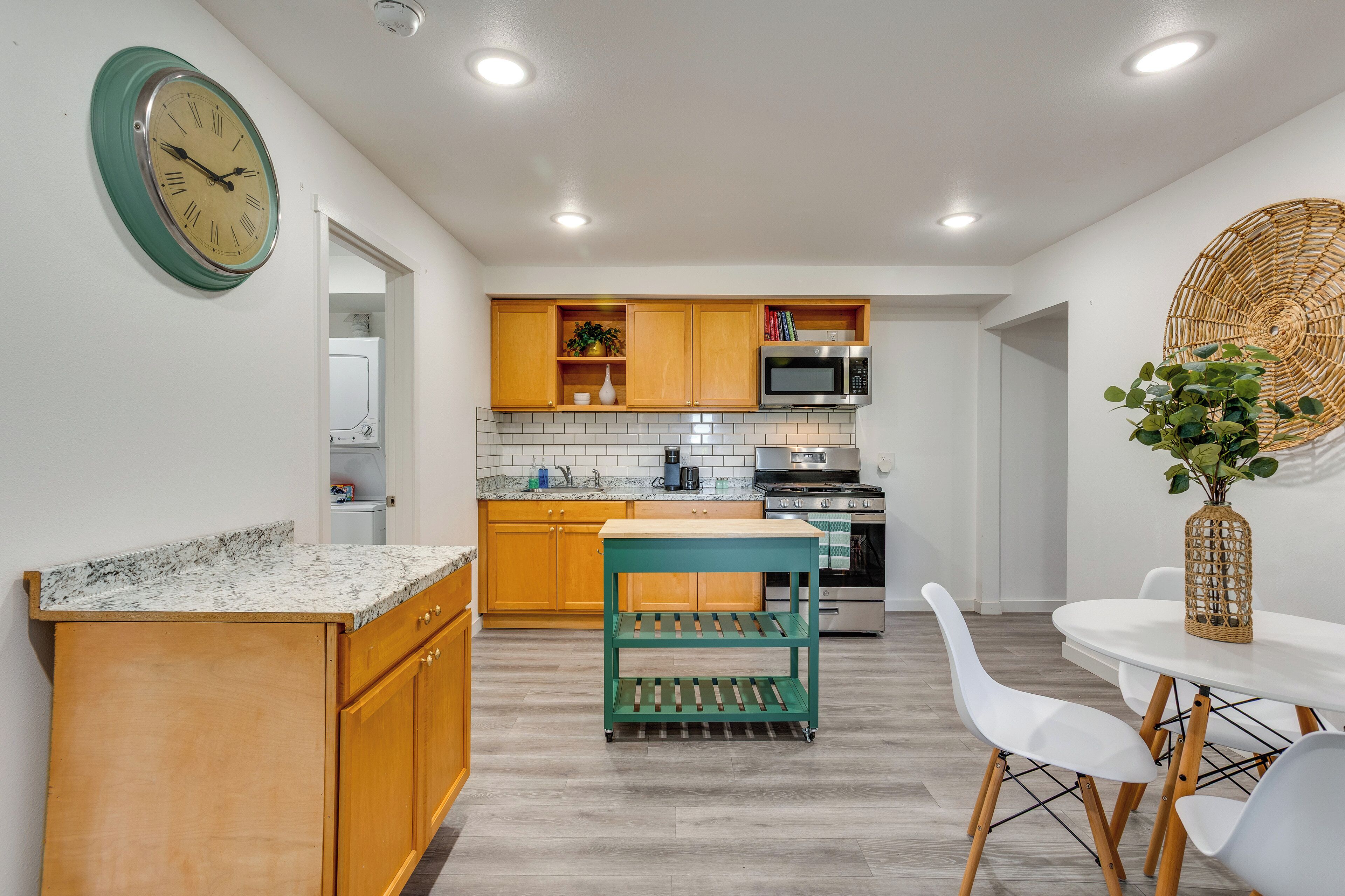 Et moderne køkken med træskabe, en grøn tralle, hvide stole og et spisebord.