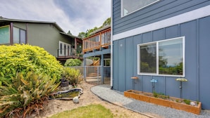 A modern two-story house with a deck, a small garden with ferns, and a gravel pathway. - Quick Hwy Access to Seattle! Mtn-View Apt w/ Yard (Renton)