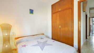 A bedroom with a bed, a wooden wardrobe, and a lamp.