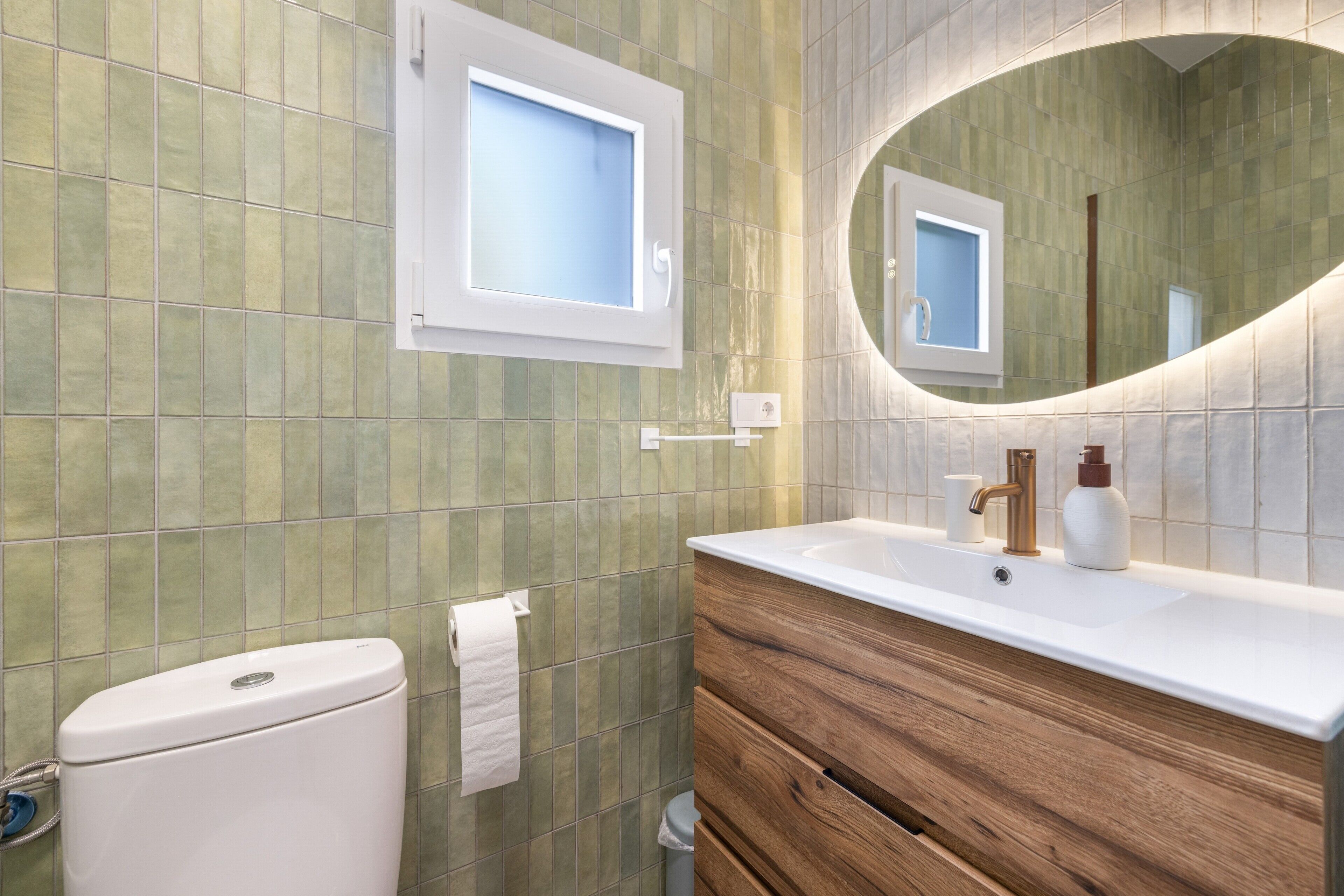 A bathroom with a toilet, a sink with a mirror, and a wooden vanity.