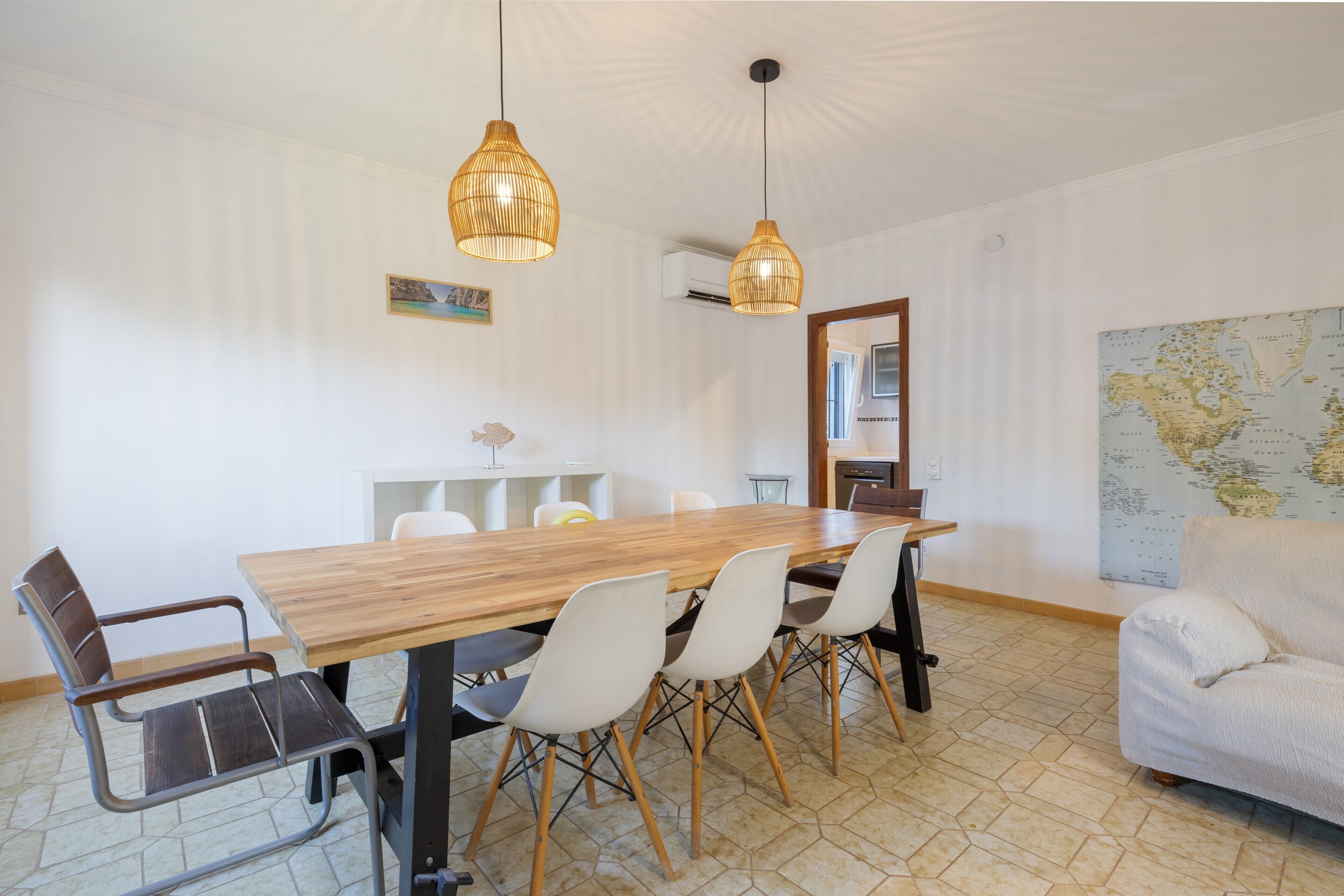 Comedor con una mesa de madera, sillas blancas y dos lámparas colgantes.