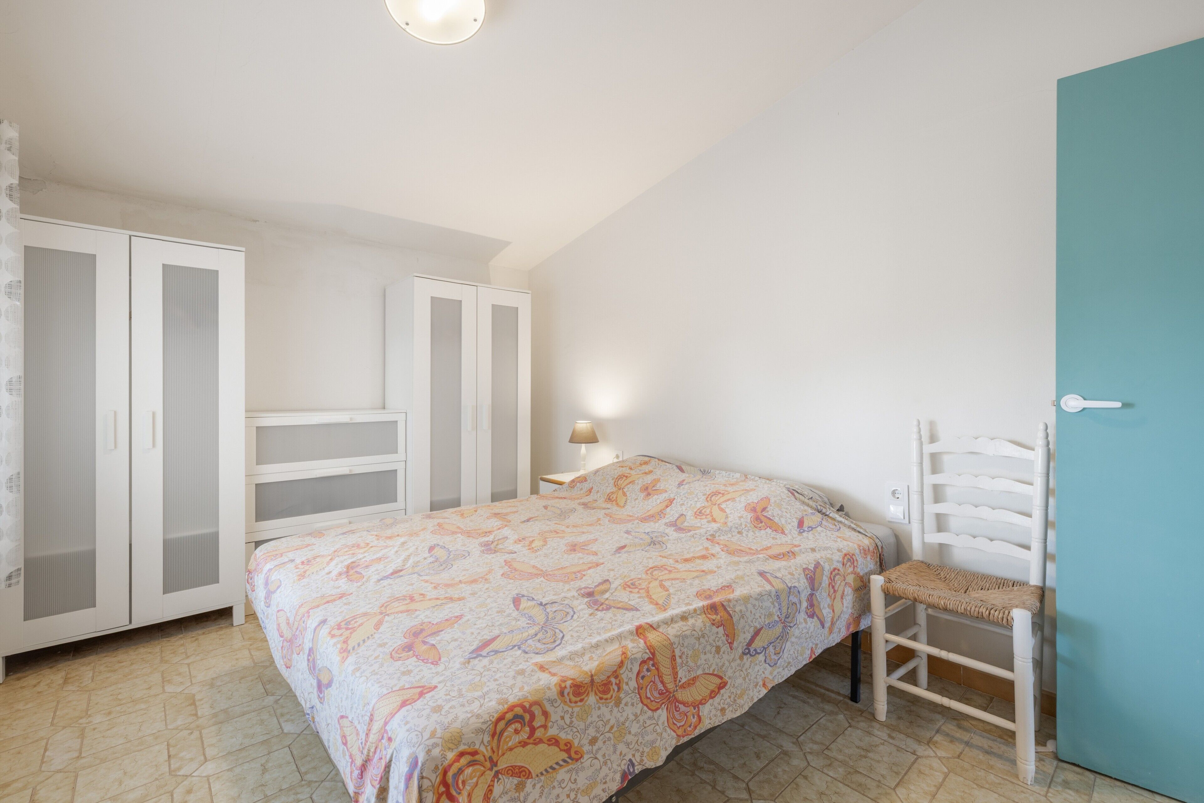 Ein Schlafzimmer mit Bett, Stuhl, Schrank und Tür.