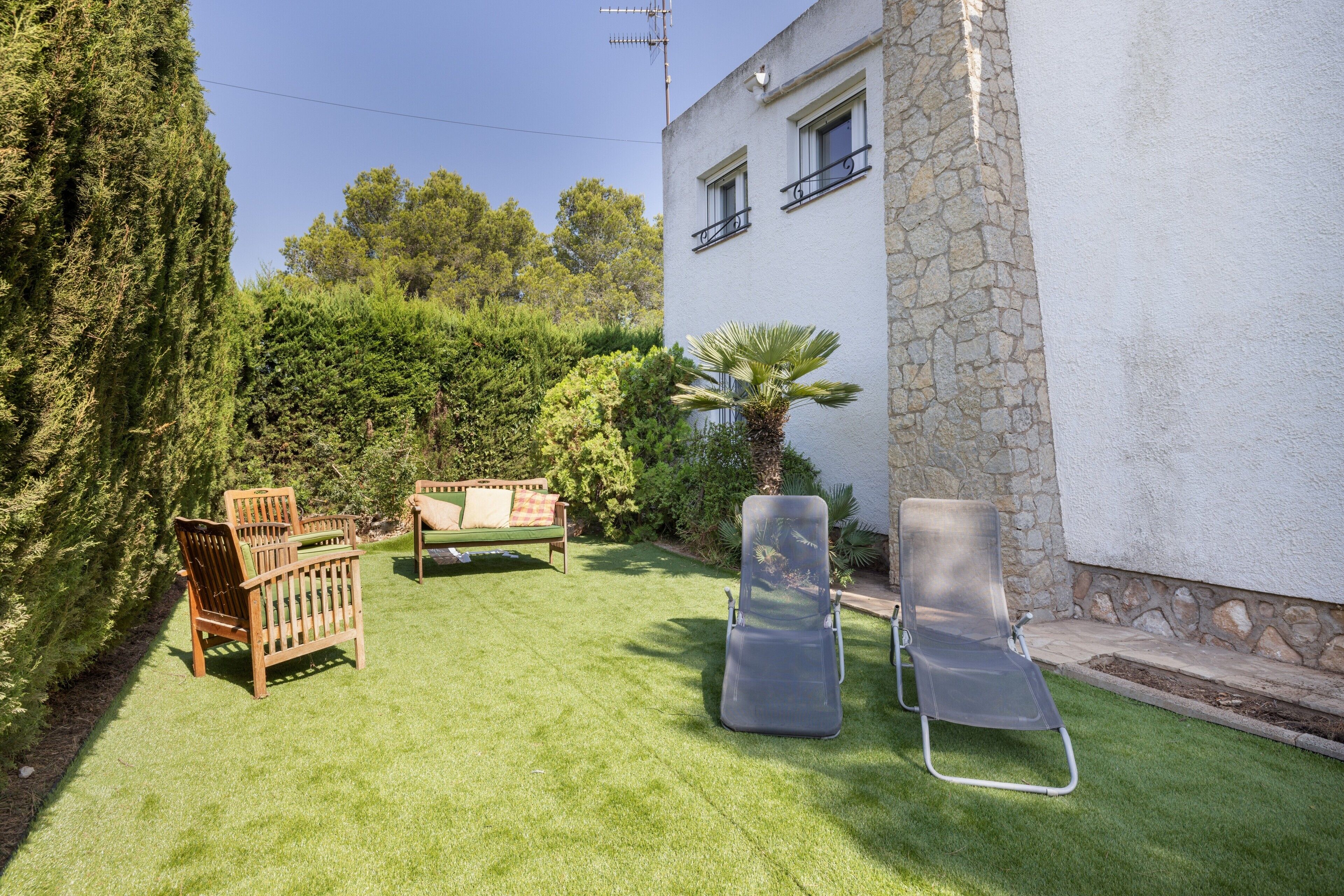 A patio with a wooden bench, a lounge chair, and a small table.