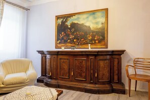 A room with a wooden cabinet, a white armchair, a wooden chair, and a painting on the wall. - Il Cipresso, Casa dei Nonni, Cortona (Cortona)