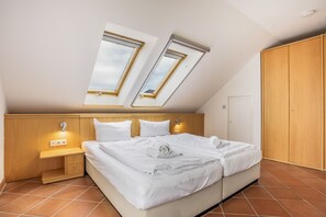 A bedroom with a bed, two bedside tables, a wardrobe, and skylights. - Holiday Apartment "Leuchtturm" – Top Floor, Large Balcony & Panoramic Achterwasser View (Mellenthin)