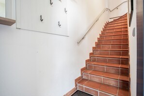 Un escalier recouvert de carreaux rouges menant à un palier.