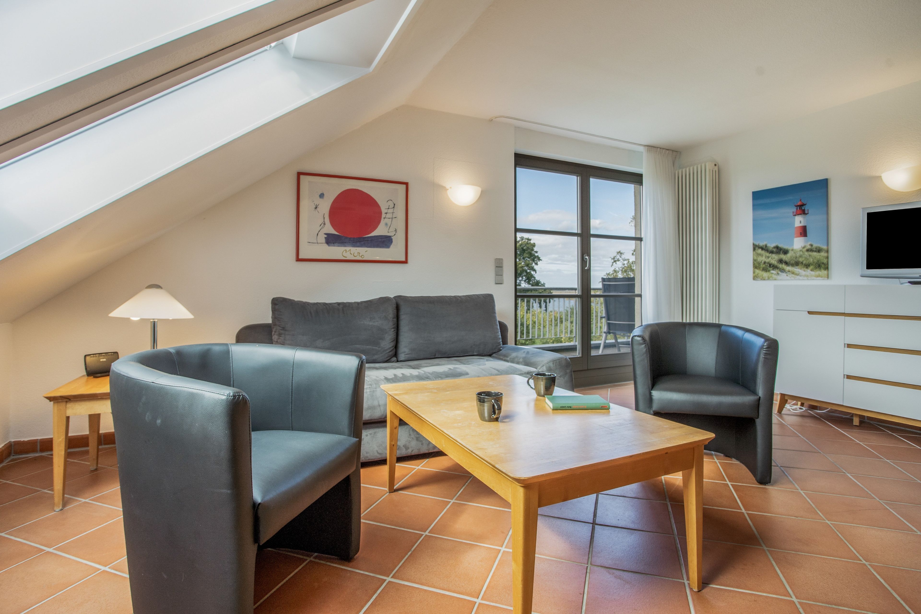 A modern living room with a sofa, two armchairs, a coffee table, and a TV.