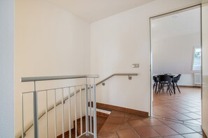 Una escalera con barandilla de metal que lleva a una habitación con una mesa de comedor y sillas.